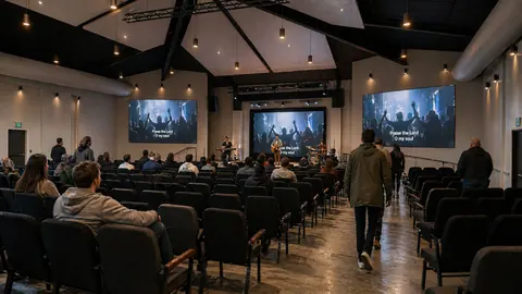 Architectural rendering of a worship service in the 3D Community Church auditorium in Sanford, NC, with three stage screens, pendant lights and fixed seating, by Ossa Studio.